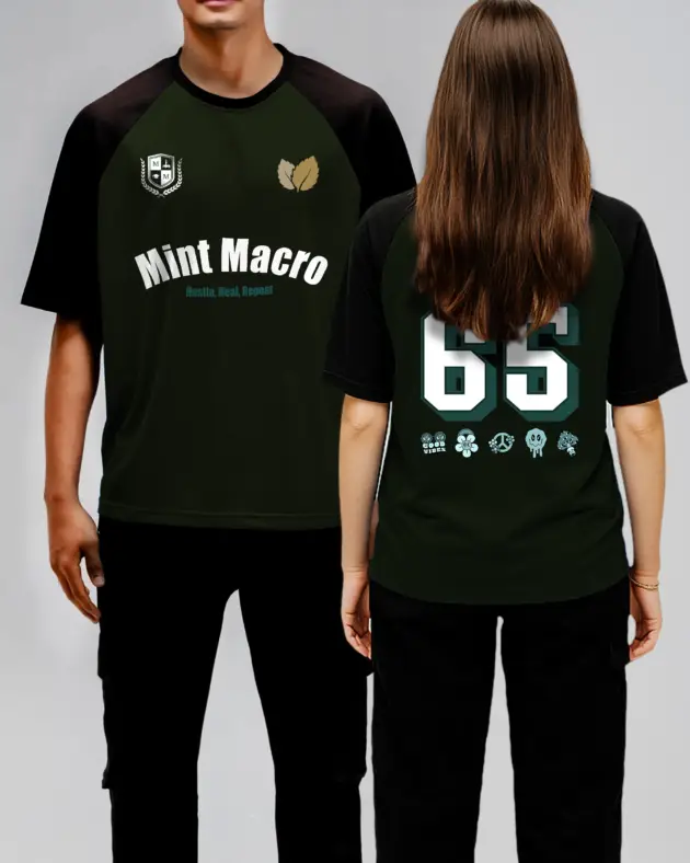 Oversized olive green and black raglan T-shirt featuring the phrase 'Hustle, Heal, Repeat' and 'Mint Macro' printed on the front, displayed on a neutral background