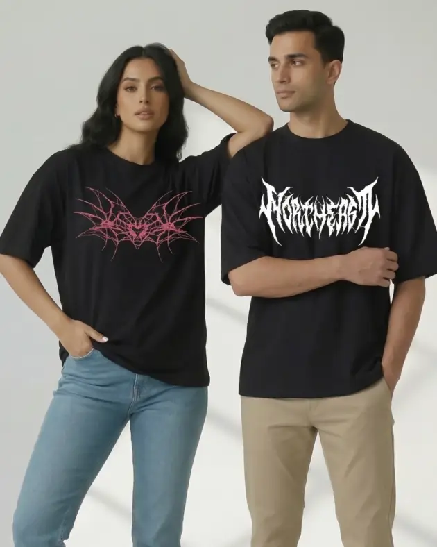 Man and woman wearing black oversized graphic t-shirts — woman in pink thorn heart print tee, man in white gothic "Northeast" logo tee, by Mint Macro Pakistan