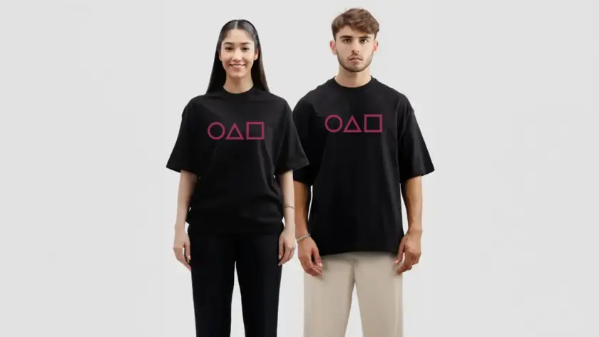 A man and a woman standing side-by-side wearing matching black oversized t-shirts featuring a pink circle, triangle, and square graphic on the chest.