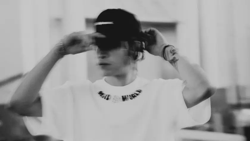 A person wearing a white oversized "MAD WORLD" streetwear t-shirt and a black baseball cap, showcasing urban fashion in Pakistan.