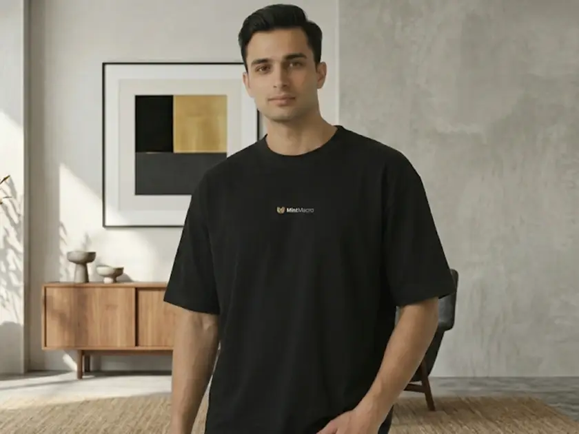 A man wearing a black Mint Macro oversized streetwear t-shirt standing in a modern, minimalist living room.