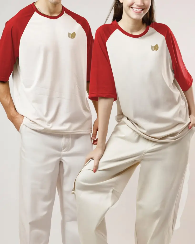 A male and female model wearing matching cream and red raglan-style oversized t-shirts with a small leaf logo, paired with off-white trousers.