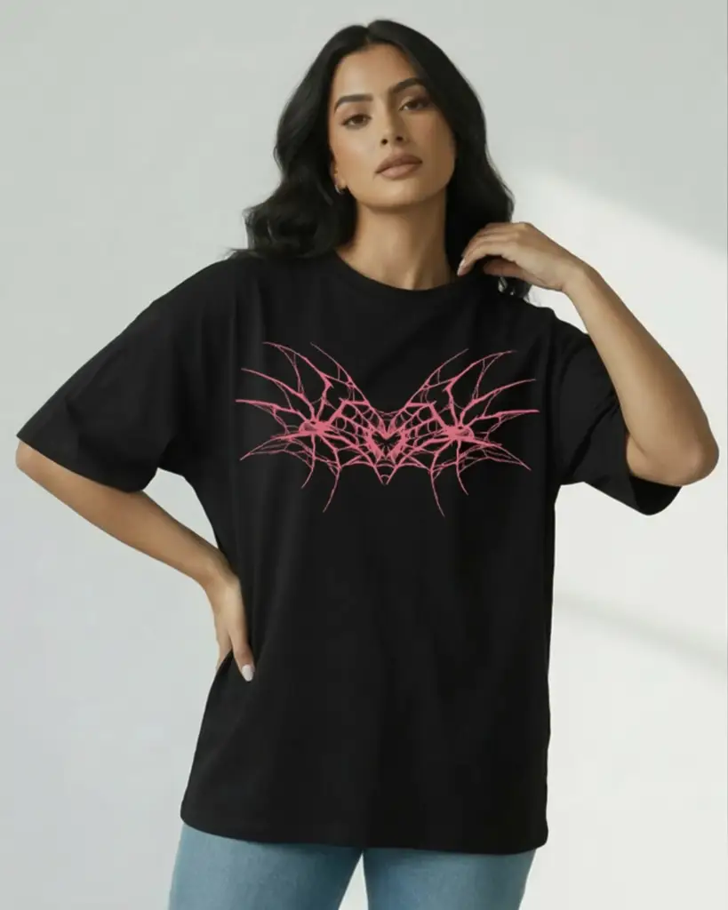 A woman modeling an oversized black t-shirt featuring a large, symmetrical pink graphic on the chest that resembles stylized wings or spiderwebs in a cyber-sigilism art style.