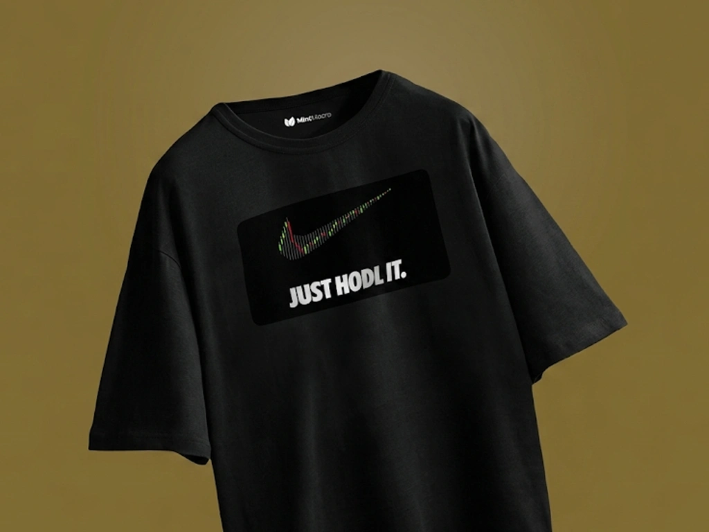 Close-up of the Mint Macro "Just HODL It" black oversized t-shirt, featuring a graphic print of a swoosh symbol made from financial candlestick charts above bold white text on an olive-gold background.