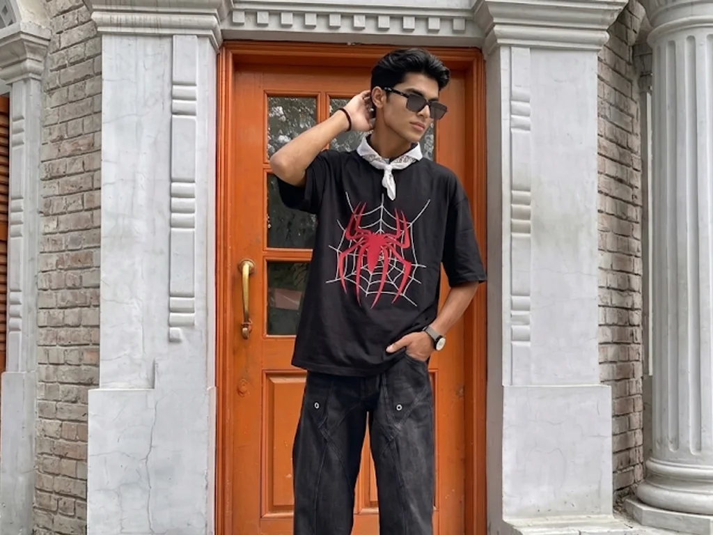 An oversized black t-shirt featuring a large, stylized red Spider-Man logo centered over a white spider web graphic.