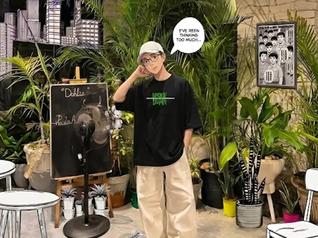 A wide landscape view of an anime-style illustrated character standing inside a unique cafe that blends real brick walls and lush green plants with 2D comic-style hand-drawn tables, chairs, and bookshelves.