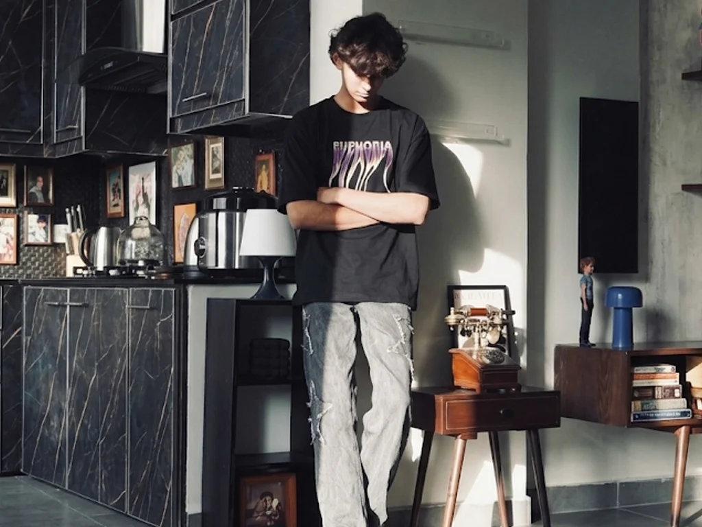 An oversized black crewneck t-shirt featuring the word "EUPHORIA" printed on the chest in a melting, distorted metallic purple and white font.